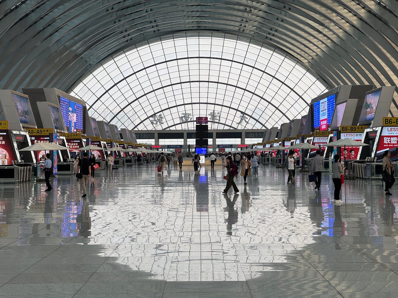 A bustling modern airport terminal with geometric ceiling design and reflective floors.